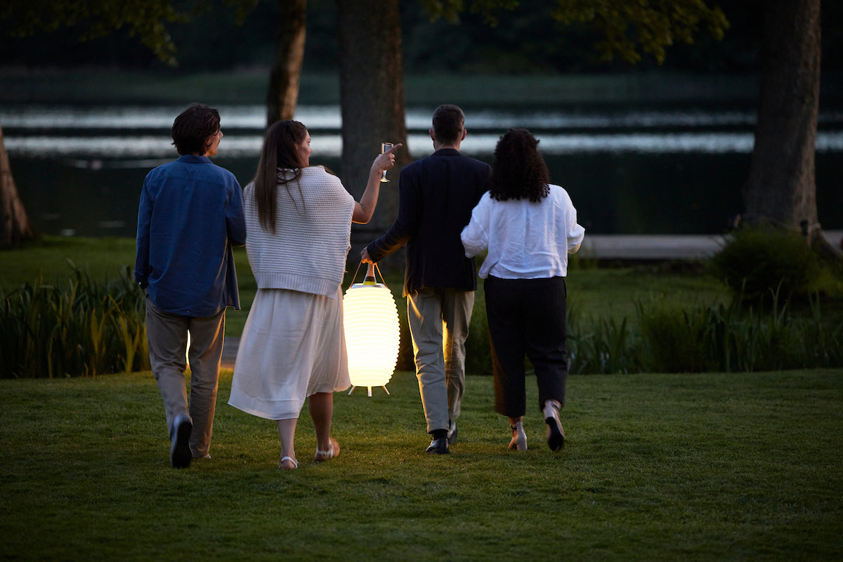 a company of two couples goes to the evening beach, carrying with them a portable lamp with a built-in wine cooler, which lights their way